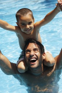 A father and son in a pool. 